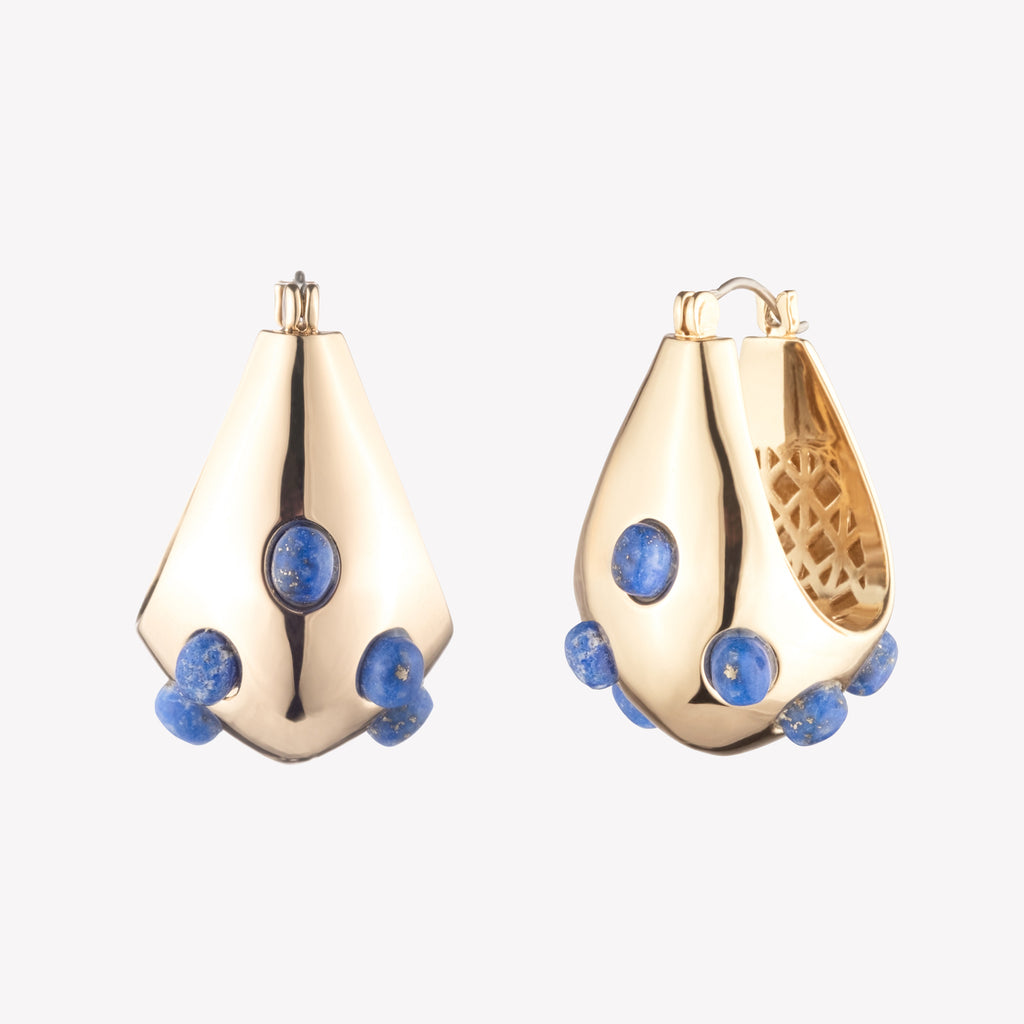 A pair of gold-colored sculptural hoop earrings with lapis lazuli cabochon stones, designed to sit close to the ear.