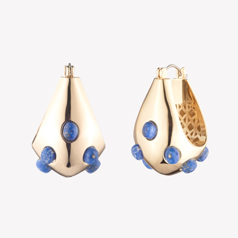 A pair of gold-colored sculptural hoop earrings with lapis lazuli cabochon stones, designed to sit close to the ear.